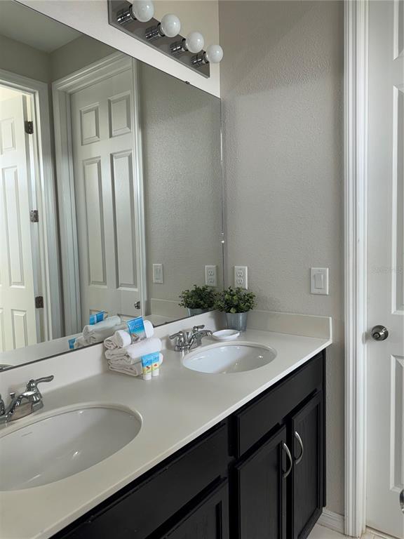 A bathroom features a double vanity with a white countertop, black cabinets, and a large mirror — 9000 EGRET MILLS TERRACE, KISSIMMEE, FL
