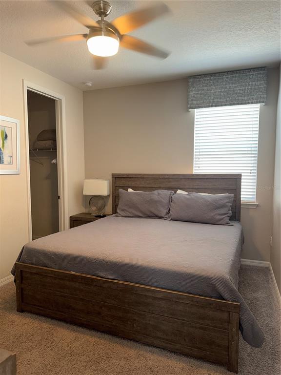 A bedroom features a wooden bed frame, a ceiling fan, and a window with blinds — 9000 EGRET MILLS TERRACE, KISSIMMEE, FL