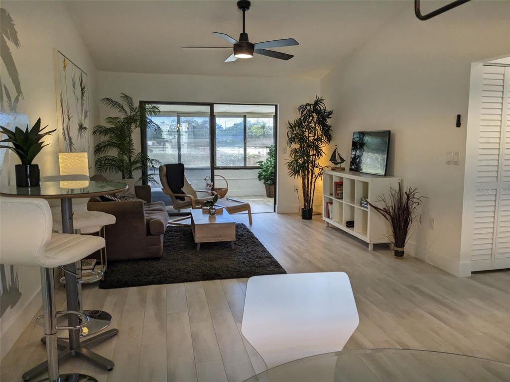 A living room features light wood flooring, a ceiling fan, and a sliding glass door — 1414 58TH STREET W, BRADENTON, FL