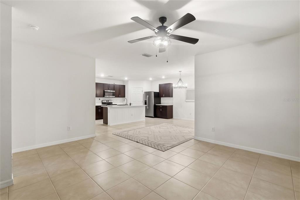A tiled living area opens into a kitchen with dark cabinets and a white island — 1782 YANKEE TERRACE, NORTH PORT, FL