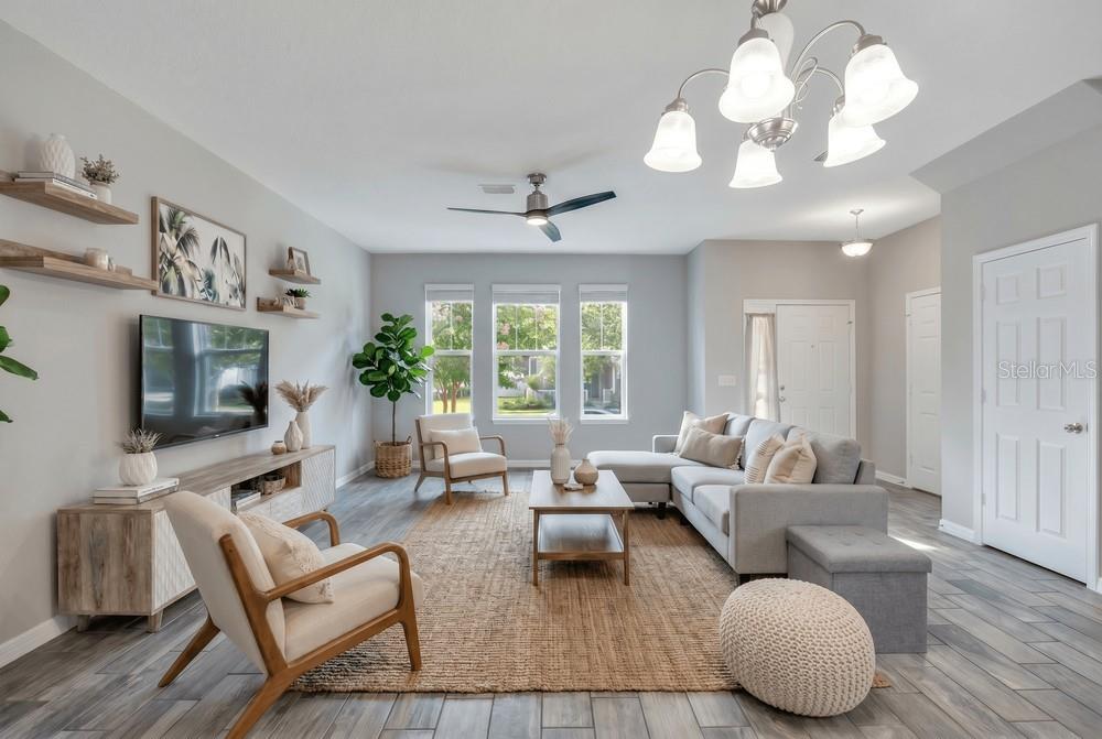 A living room features a grey sectional sofa, wood-framed armchairs, a jute rug, and shelving — 8150 RED STOPPER LANE, WINTER GARDEN, FL
