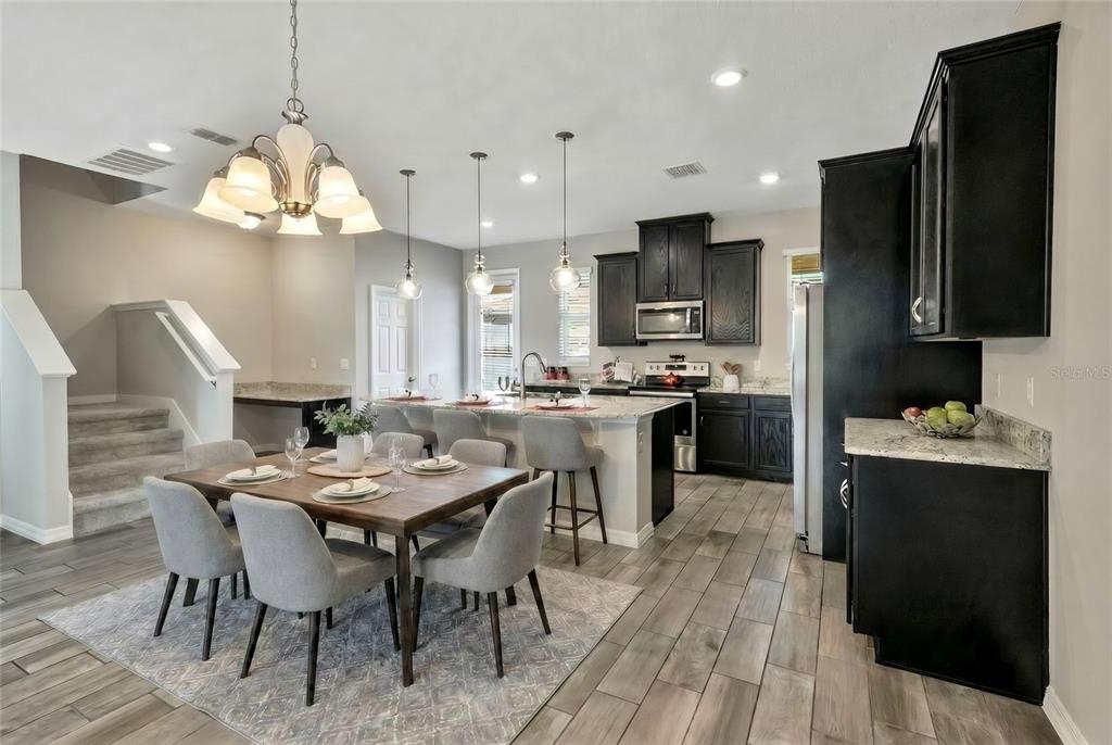 A kitchen and dining area with dark cabinets, a center island, and wood-look tile flooring — 8150 RED STOPPER LANE, WINTER GARDEN, FL