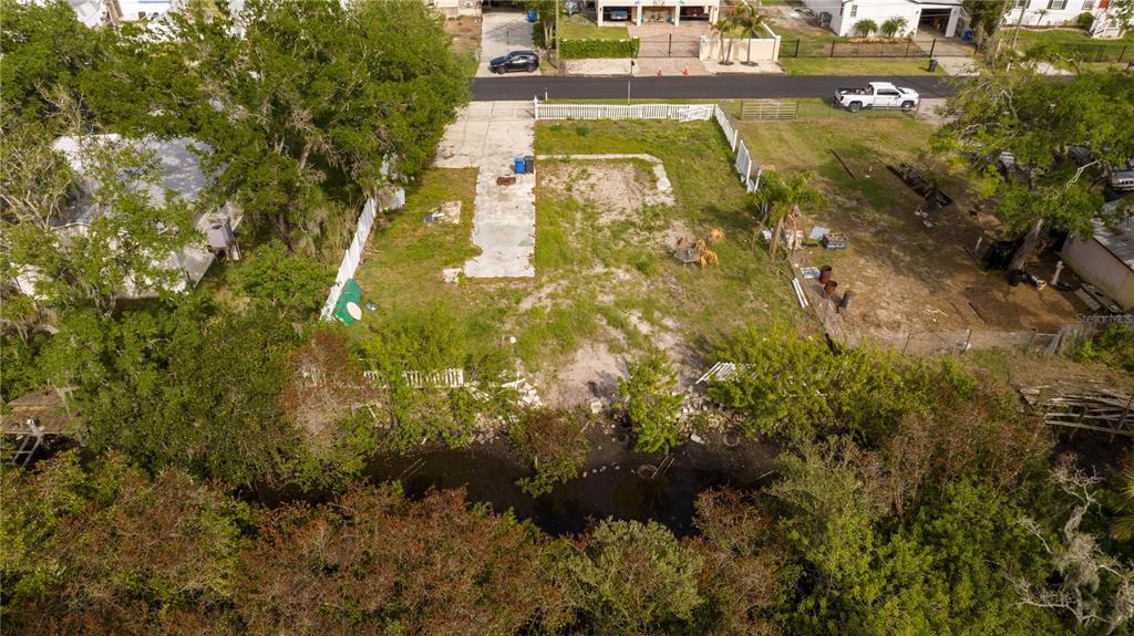 An aerial view shows a vacant residential lot with a concrete driveway leading to water — 9923 ALAVISTA DRIVE, GIBSONTON, FL