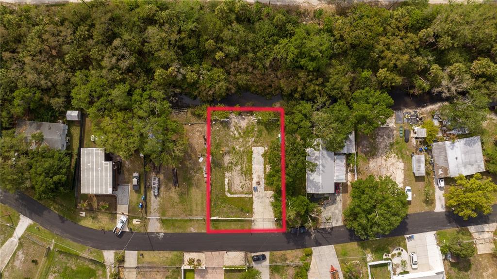 An aerial view shows a vacant rectangular lot outlined in red between two residential properties — 9923 ALAVISTA DRIVE, GIBSONTON, FL