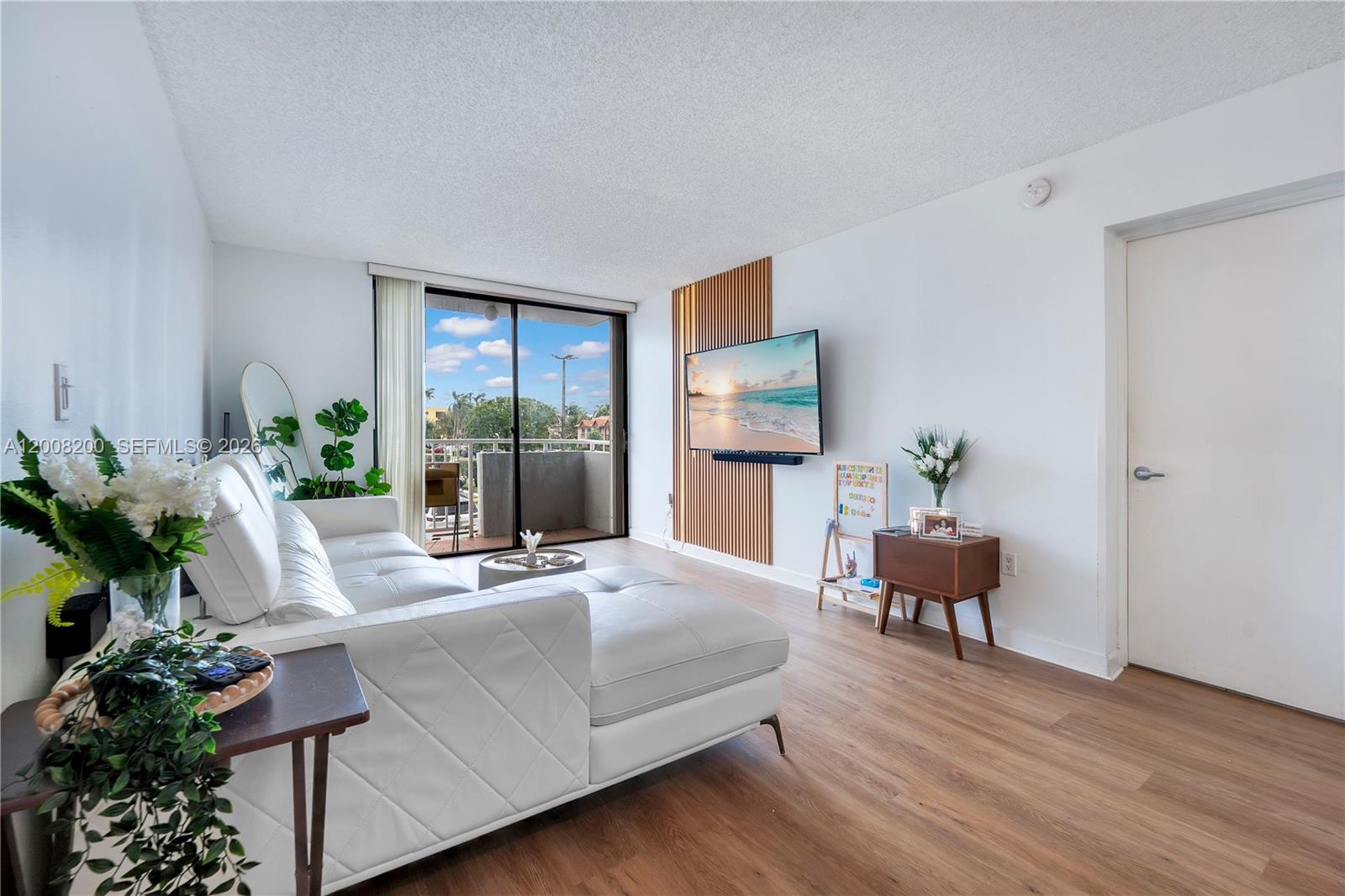 A living room features a white sectional sofa, wood-slat wall paneling, and a sliding glass door — 8261 NW 8th St # 231, Miami FL 33126, MIAMI, FL