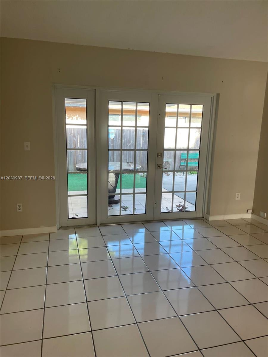 A room with white tile flooring features a set of glass-paned French doors leading outside — 13413 SW 116th Ct # 0, Miami FL 33176, MIAMI, FL