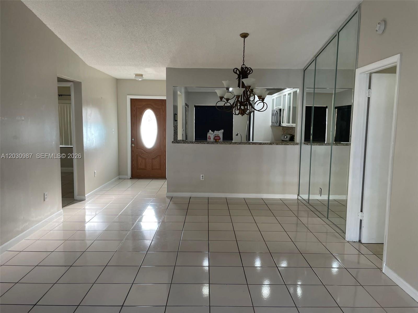 A tiled dining area features a chandelier, a kitchen pass-through window, and mirrored closet doors — 13413 SW 116th Ct # 0, Miami FL 33176, MIAMI, FL