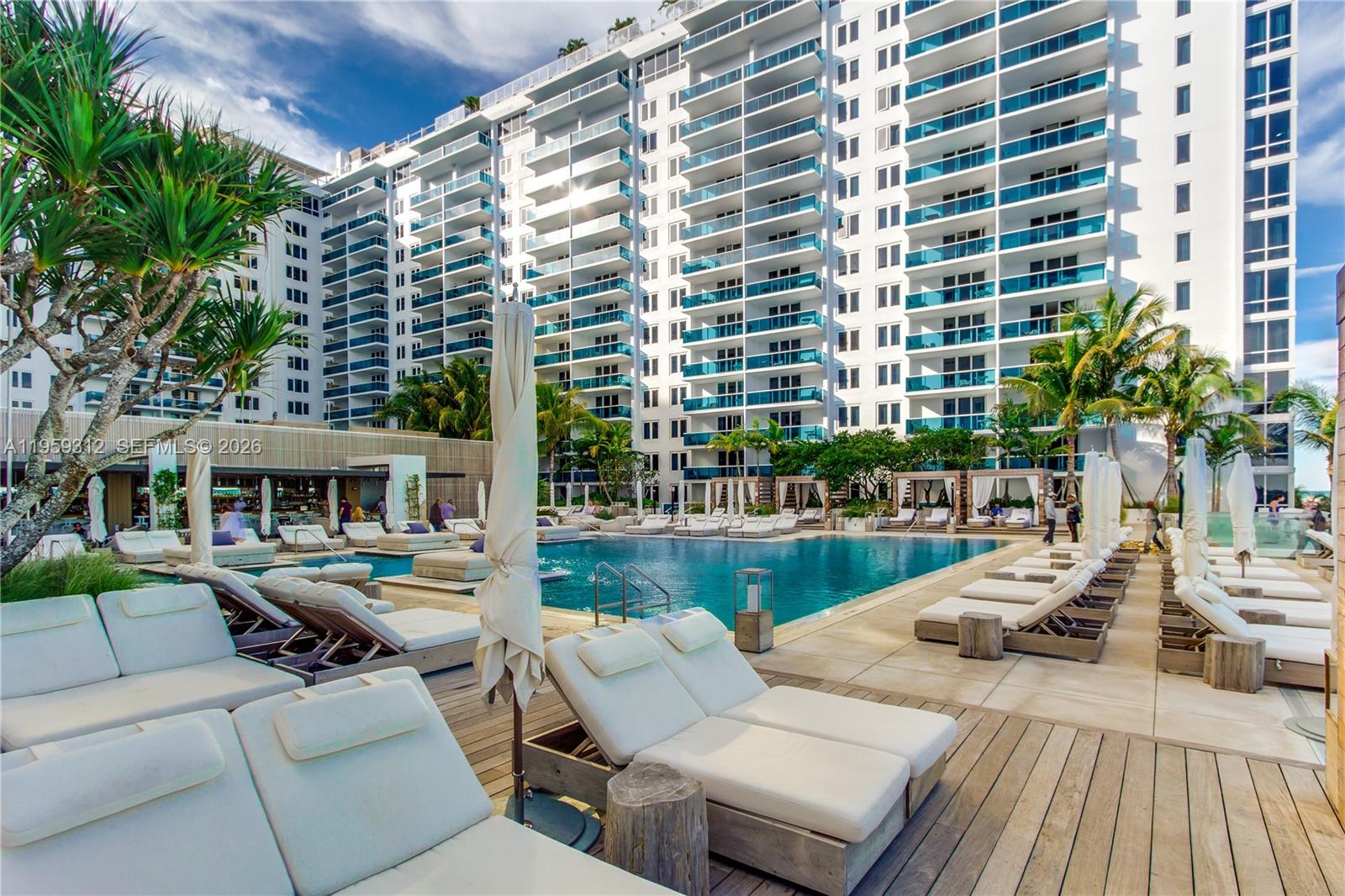 A living room features a beige sofa, a natural wood coffee table, and a wicker chair — 102 24th St # 1206, Miami Beach FL 33139, MIAMI BEACH, FL