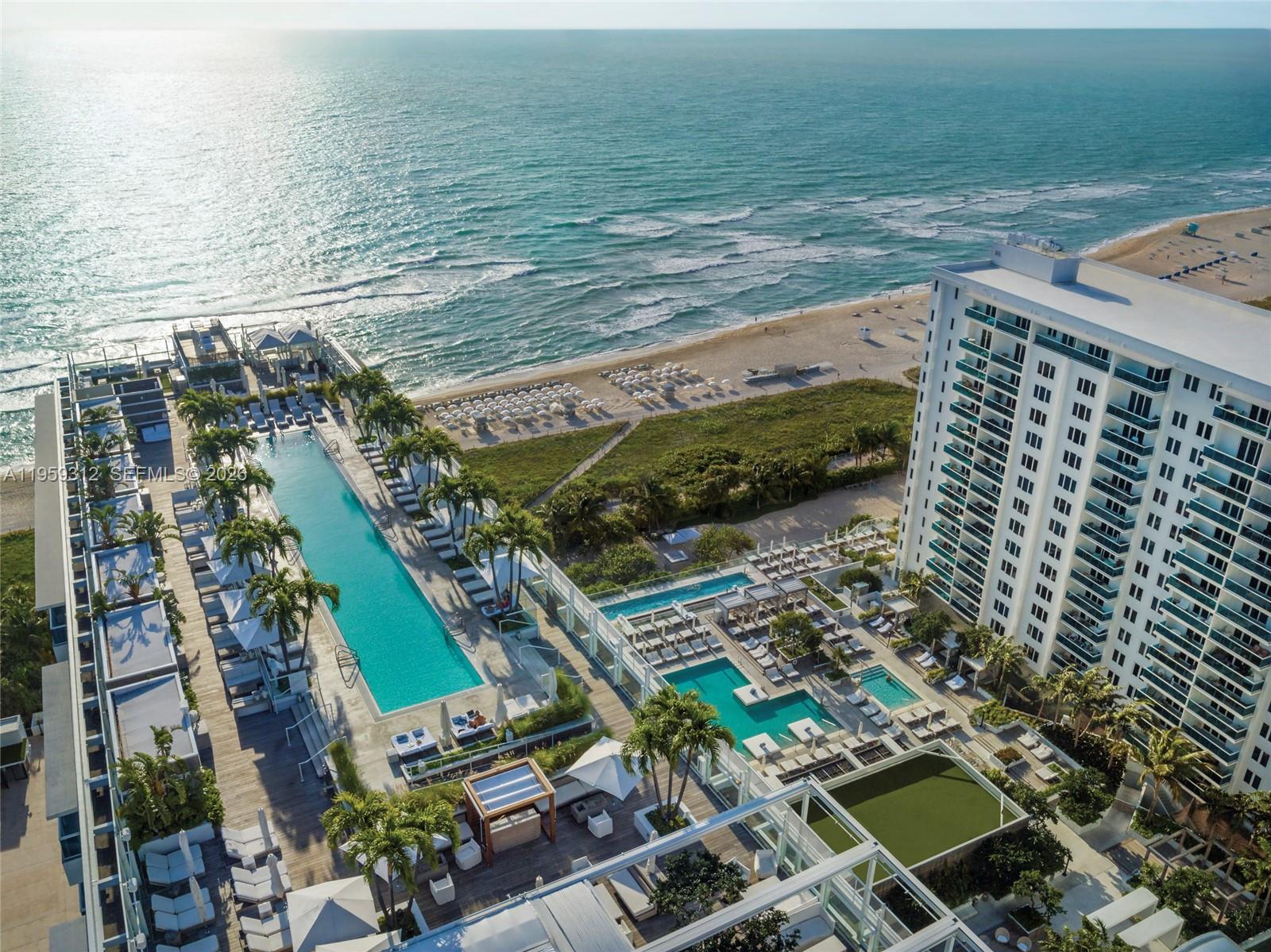 A living room features a light wood media wall with built-in shelves and ocean views — 102 24th St # 1206, Miami Beach FL 33139, MIAMI BEACH, FL