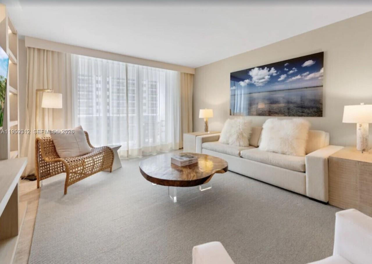 A modern living room features light wood built-in shelving, a wall-mounted television, and neutral furniture — 102 24th St # 1206, Miami Beach FL 33139, MIAMI BEACH, FL