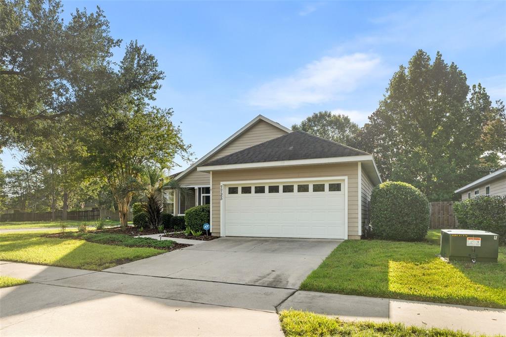 A tan single-story house with a white garage door and a concrete driveway — 7725 SW 87TH TERRACE, GAINESVILLE, FL