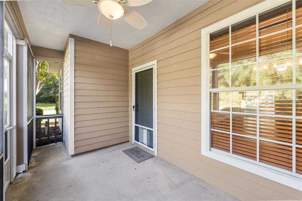 A covered porch with beige siding, a ceiling fan, a screen door, and a large window — 7725 SW 87TH TERRACE, GAINESVILLE, FL