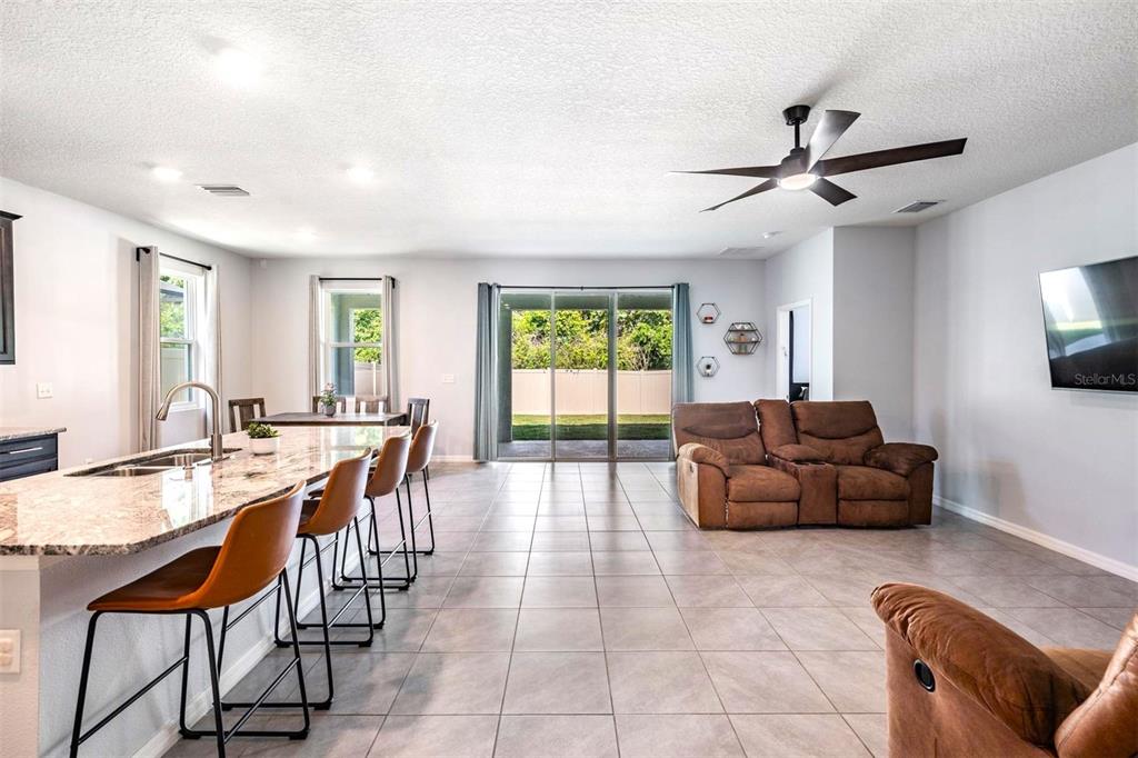 A spacious open-concept kitchen and living area with tile floors and a ceiling fan — 16619 GOOSE RIBBON PLACE, WIMAUMA, FL