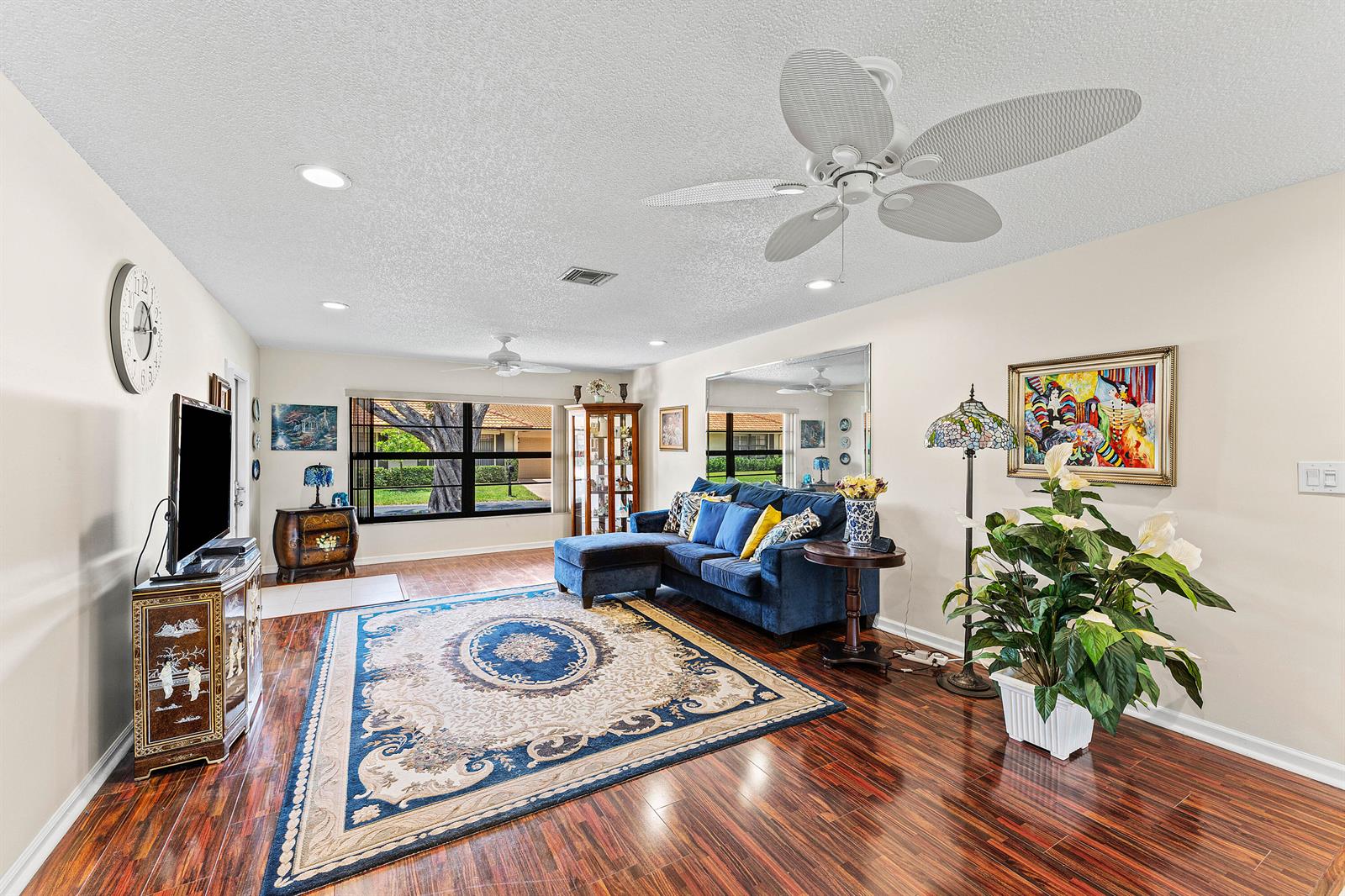 A living room features a blue sectional sofa, a large area rug, and hardwood floors — 4520 Ficus Tree Road, Boynton Beach FL 33436, BOYNTON BEACH, FL