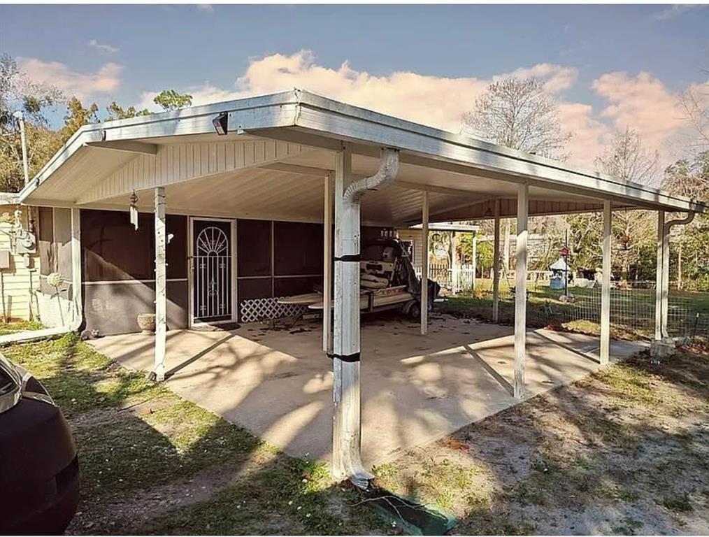 A covered concrete carport attached to a home with a screened-in porch and metal roof — 10119 E BASS CIRCLE, INVERNESS, FL
