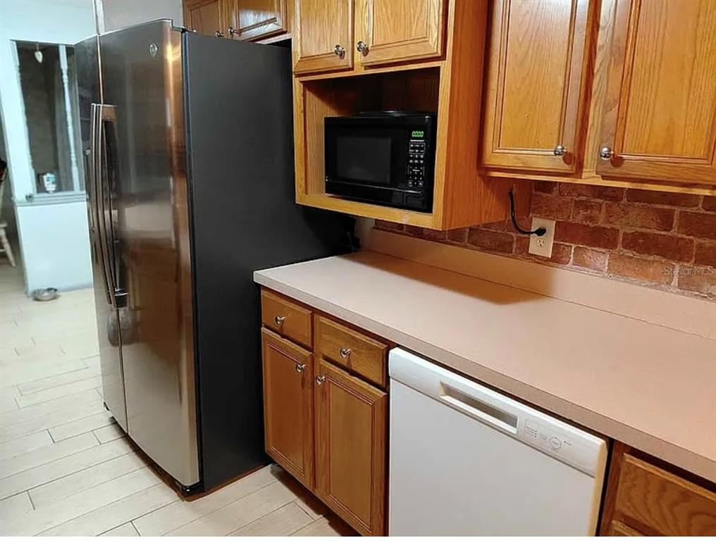 A kitchen features wood cabinets, a black refrigerator, a microwave, and a white dishwasher — 10119 E BASS CIRCLE, INVERNESS, FL