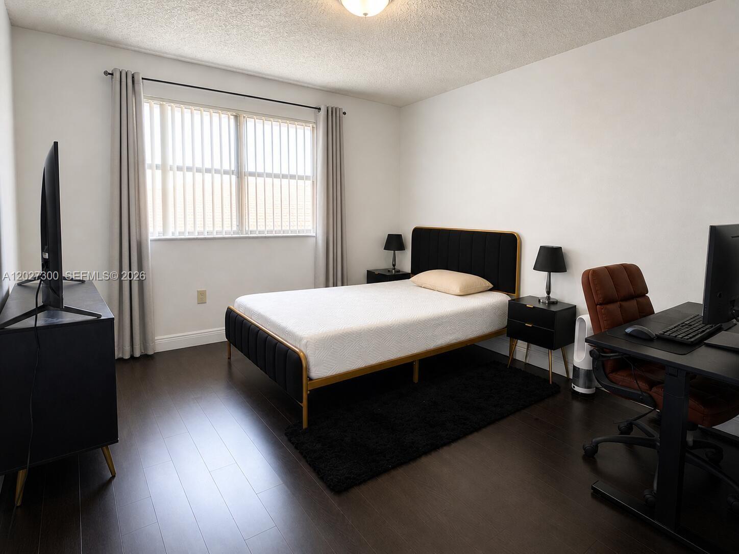 A bedroom features a bed, two nightstands, a desk, and a television on dark flooring — 15540 SW 80th St # 304, Miami FL 33193, MIAMI, FL