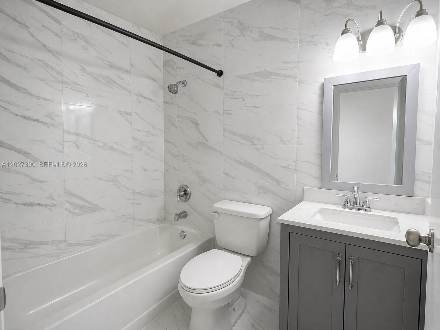 A bathroom features a gray vanity, a white toilet, and a bathtub with marble-patterned tile — 15540 SW 80th St # 304, Miami FL 33193, MIAMI, FL