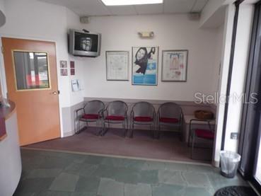 A waiting room features a row of chairs, wall art, and a mounted television — 2921 S ORLANDO DRIVE UNIT 146, SANFORD, FL
