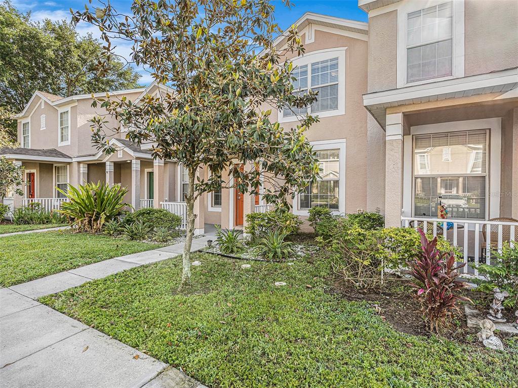 A two-story townhouse with a beige stucco exterior, a front porch, and a landscaped yard — 507 BROKEN LIMB PLACE, BRANDON, FL