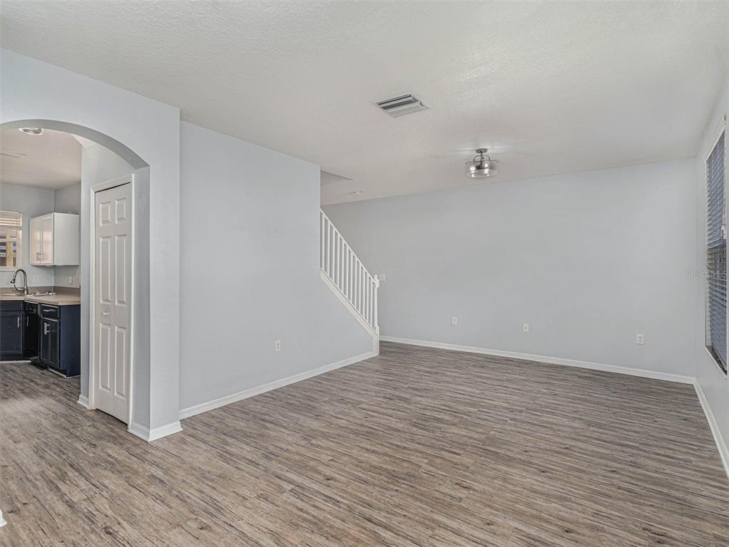 A living room with light gray walls, wood-look flooring, and a staircase with white railings — 507 BROKEN LIMB PLACE, BRANDON, FL