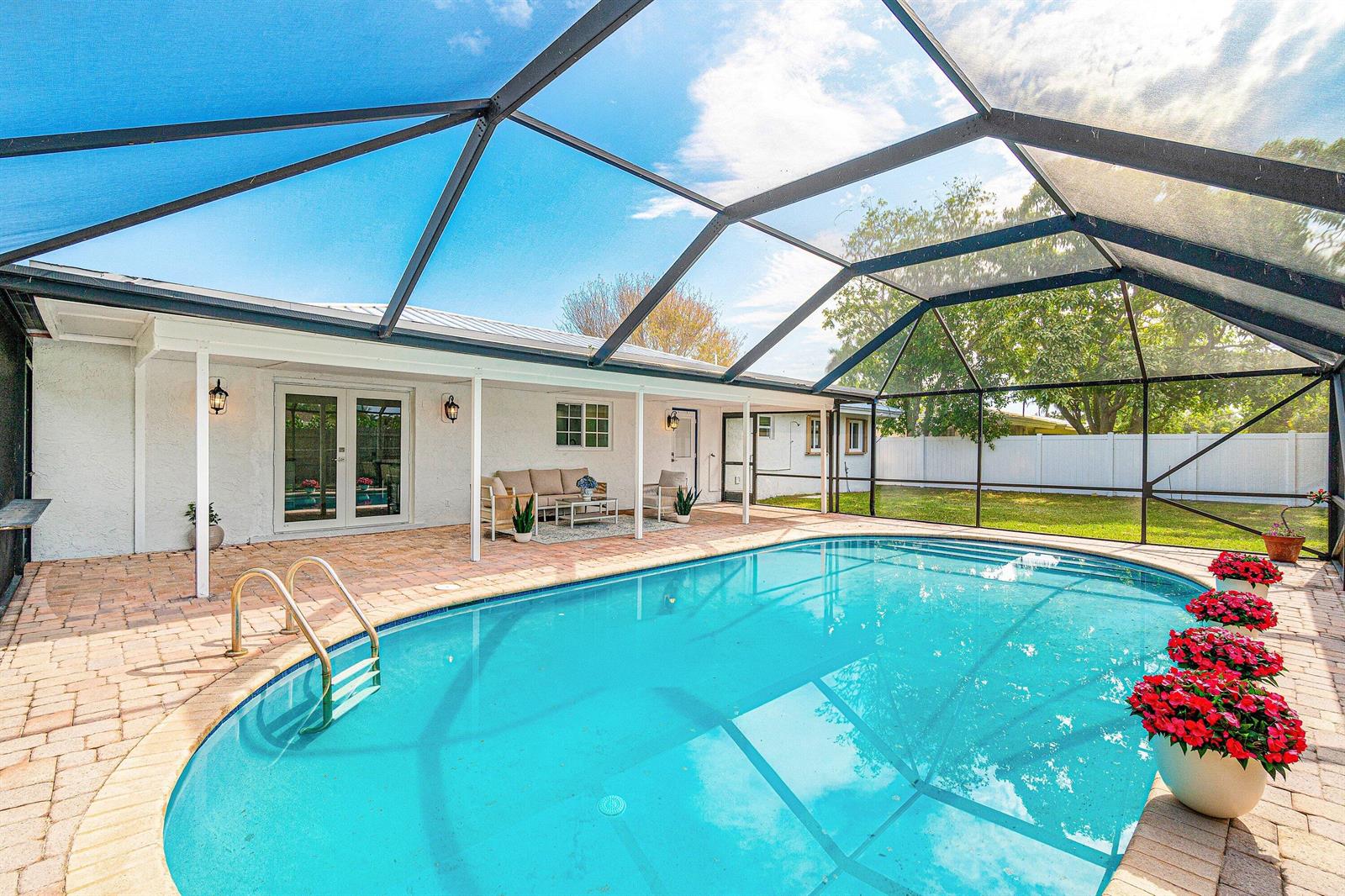 A swimming pool with a screened enclosure sits on a brick patio behind a house — 718 SW 27th Place, Boynton Beach FL 33435, BOYNTON BEACH, FL