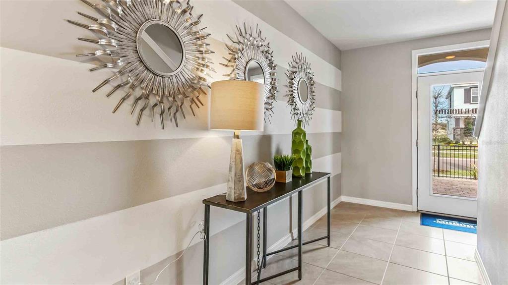 A foyer features a console table, three sunburst mirrors, and horizontal striped walls — 7114 FLINT CREEK DRIVE, LAND O LAKES, FL