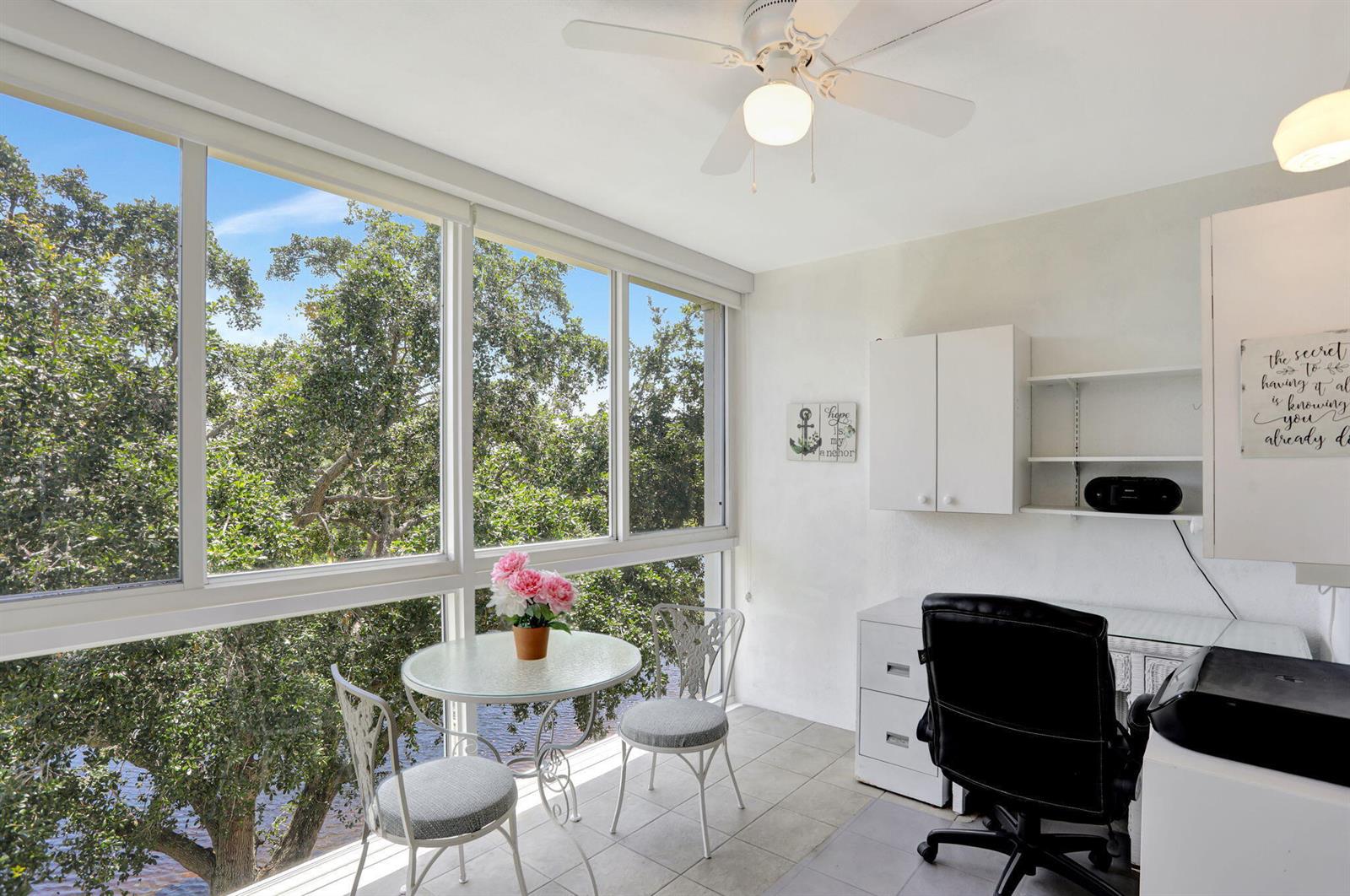 A sunroom features a small dining table, a desk with a chair, and large windows — 432 Grantham # B, Deerfield Beach FL 33442, DEERFIELD BEACH, FL