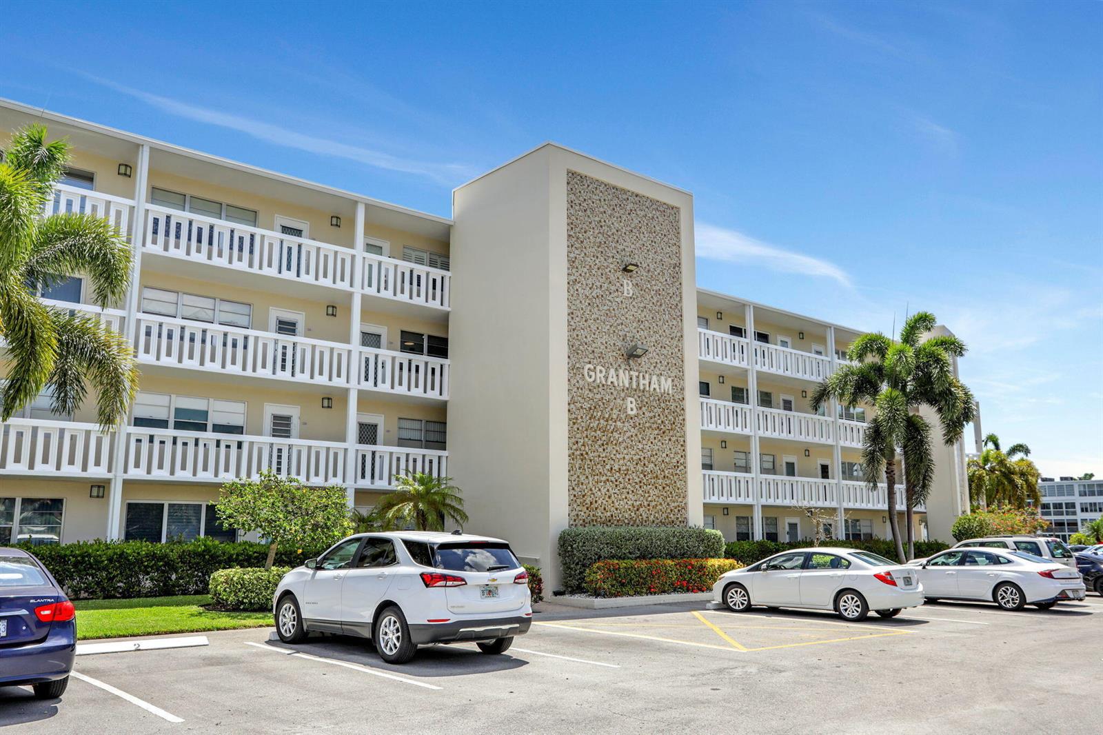 The exterior of a multi-story residential building features a textured facade and a parking lot — 432 Grantham # B, Deerfield Beach FL 33442, DEERFIELD BEACH, FL