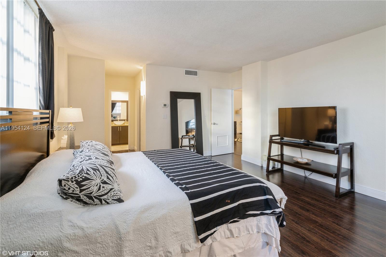 A bedroom features a bed with a striped runner, dark wood floors, and a television — 4001 S Ocean Dr # 10B, Hollywood FL 33019, HOLLYWOOD, FL