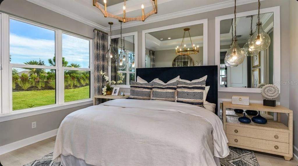 A bedroom features a dark blue headboard, large wall mirrors, pendant lights, and bedside tables — 14521 DERNA TERRACE, BRADENTON, FL