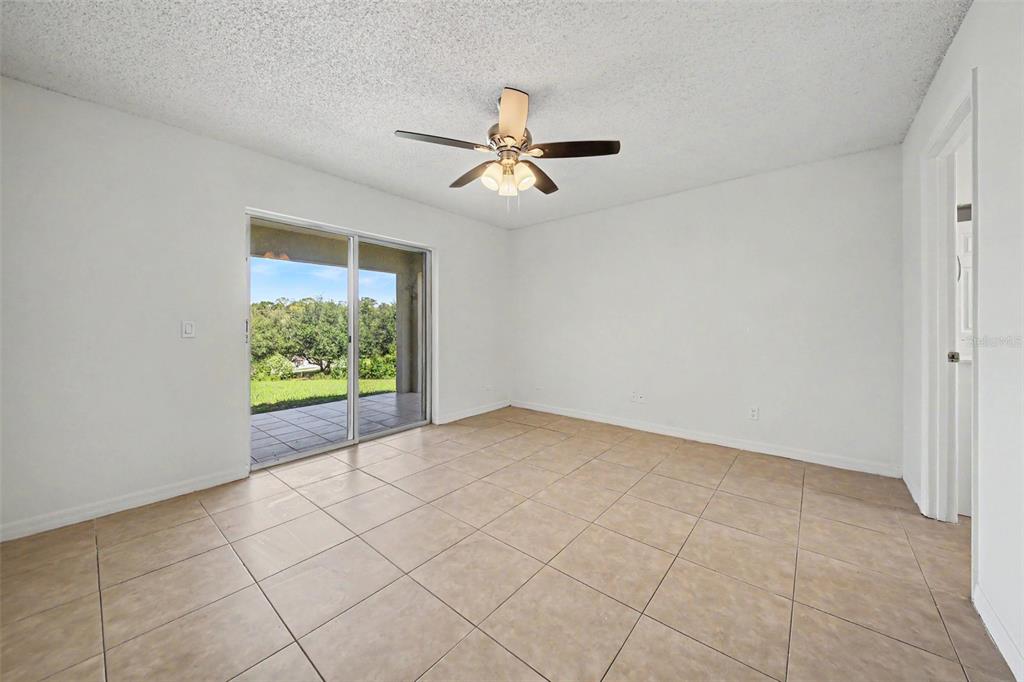 An empty room with beige tile flooring, a ceiling fan, and sliding glass patio doors — 1067 SHEELER HILLS DRIVE, APOPKA, FL