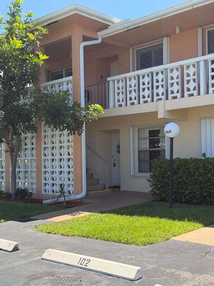 A two-story apartment building exterior features a decorative concrete block screen and a parking space — 1360 NW 19th Terrace # 101, Delray Beach FL 33445, DELRAY BEACH, FL