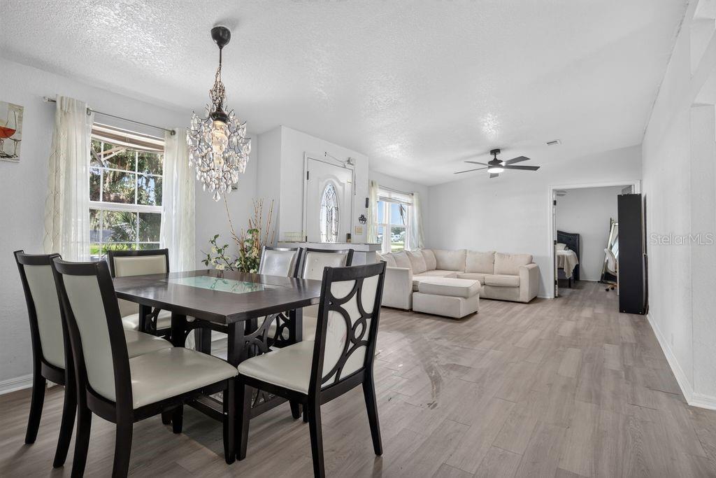 A dining area with a crystal chandelier flows into a living room with light flooring — 4612 TURNER ROAD, MULBERRY, FL