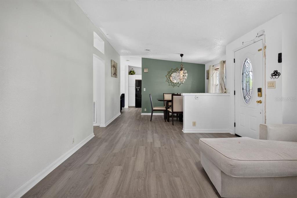 A living room with wood-look flooring leads to a dining area with a green accent wall — 4612 TURNER ROAD, MULBERRY, FL