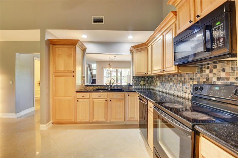 A kitchen with light wood cabinets, black appliances, and a mosaic tile backsplash — 9316 Ketay Circle, Boca Raton FL 33428, BOCA RATON, FL