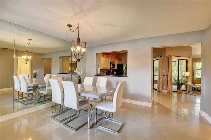 A dining room features a mirrored wall, a modern chandelier, and a pass-through to the kitchen — 9316 Ketay Circle, Boca Raton FL 33428, BOCA RATON, FL