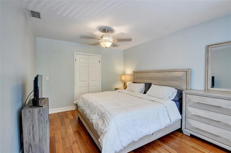 A bedroom features a bed with a headboard, a dresser with a mirror, and wood flooring — 9316 Ketay Circle, Boca Raton FL 33428, BOCA RATON, FL