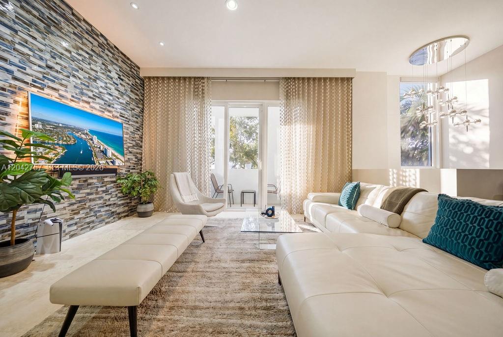 A modern living room features a stone accent wall, white leather furniture, and floor-to-ceiling curtains — 710 NE 3rd Ave, Fort Lauderdale FL 33304, FORT LAUDERDALE, FL