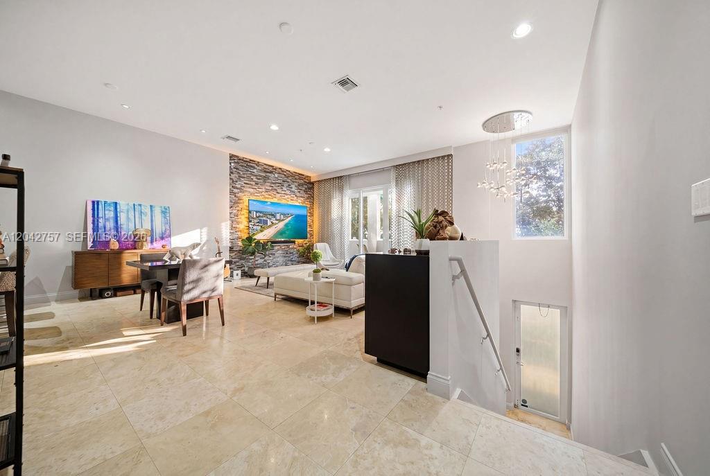 A modern living room features stone wall accents, tile flooring, and a staircase leading downward — 710 NE 3rd Ave, Fort Lauderdale FL 33304, FORT LAUDERDALE, FL
