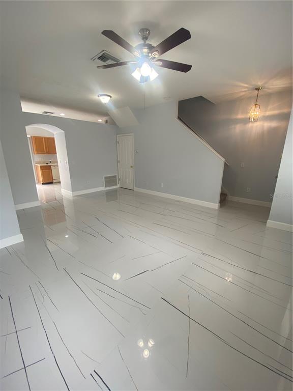 A living area features light gray walls, white marble-look tile flooring, and a ceiling fan — 10103 BELLEVILLE PLACE, TAMPA, FL