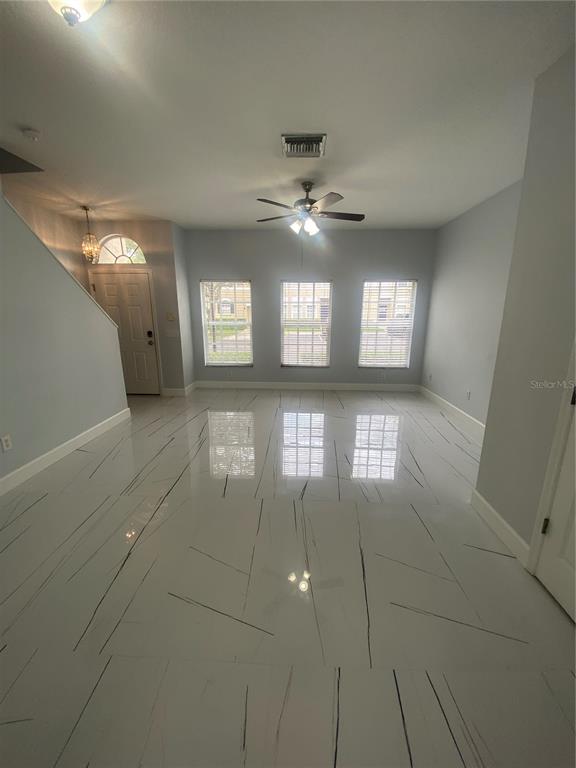 A living room with light gray walls, white marble-look tile flooring, and a ceiling fan — 10103 BELLEVILLE PLACE, TAMPA, FL