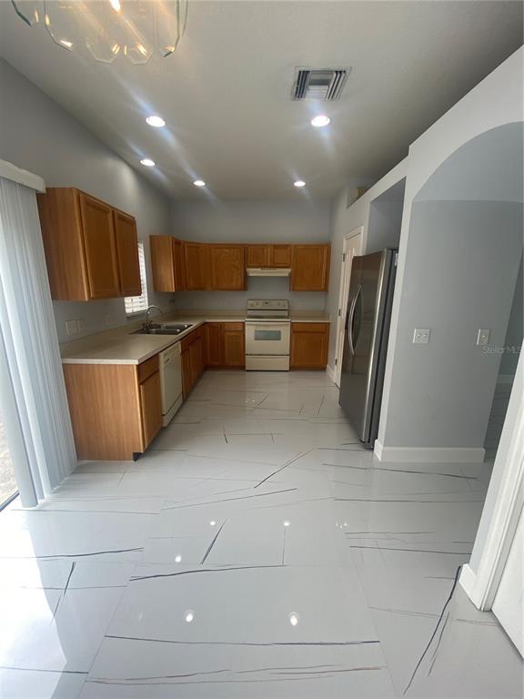 A kitchen features light wood cabinets, white countertops, stainless steel appliances, and white marble-patterned flooring — 10103 BELLEVILLE PLACE, TAMPA, FL