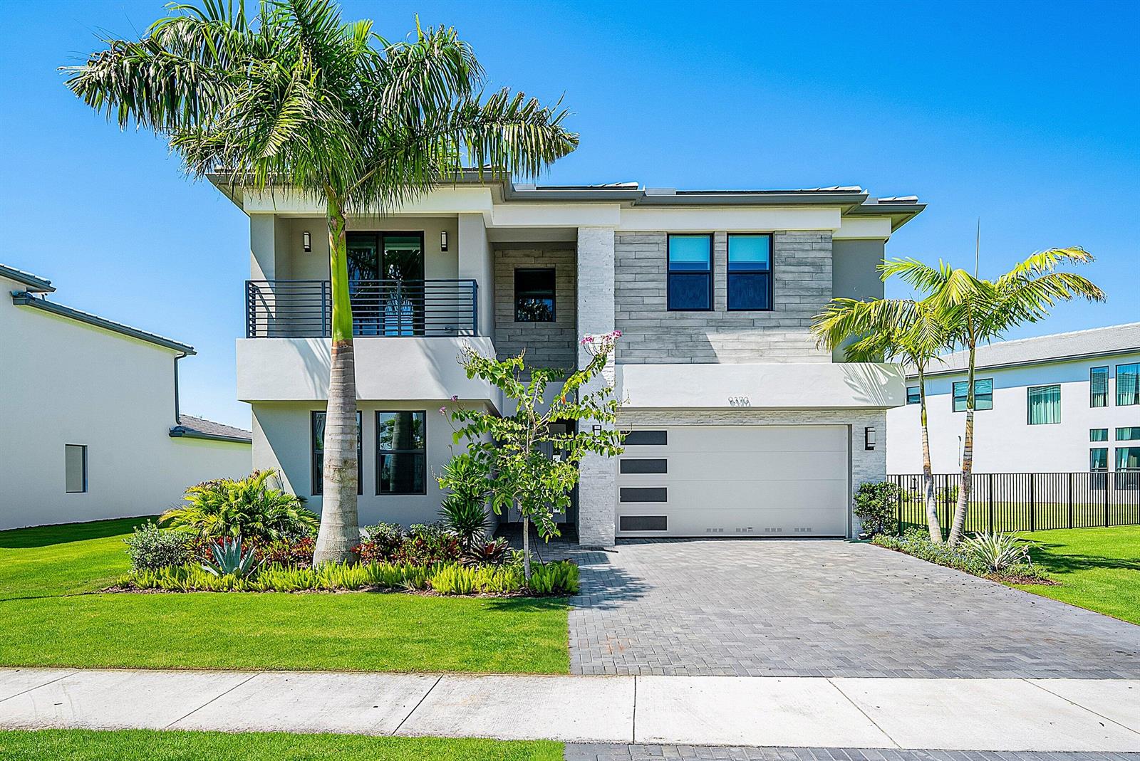 A two-story modern house with a paved driveway, palm trees, and a white garage door — 9370 Sunflower Meadow Road, Boca Raton FL 33434, BOCA RATON, FL