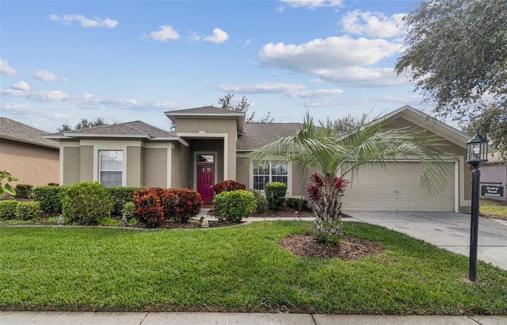 A single-story house with a tan stucco exterior, a magenta front door, and a garage — 18902 GRAND CLUB DRIVE, HUDSON, FL
