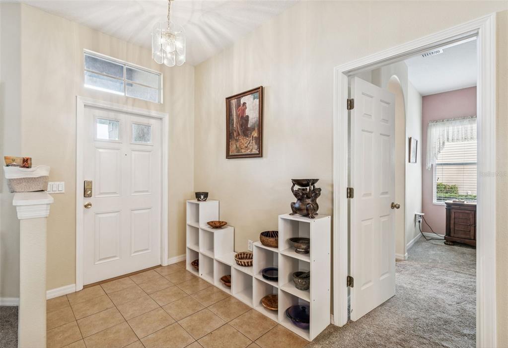 An entryway with tile flooring, a white front door, and a tiered white storage shelf — 18902 GRAND CLUB DRIVE, HUDSON, FL