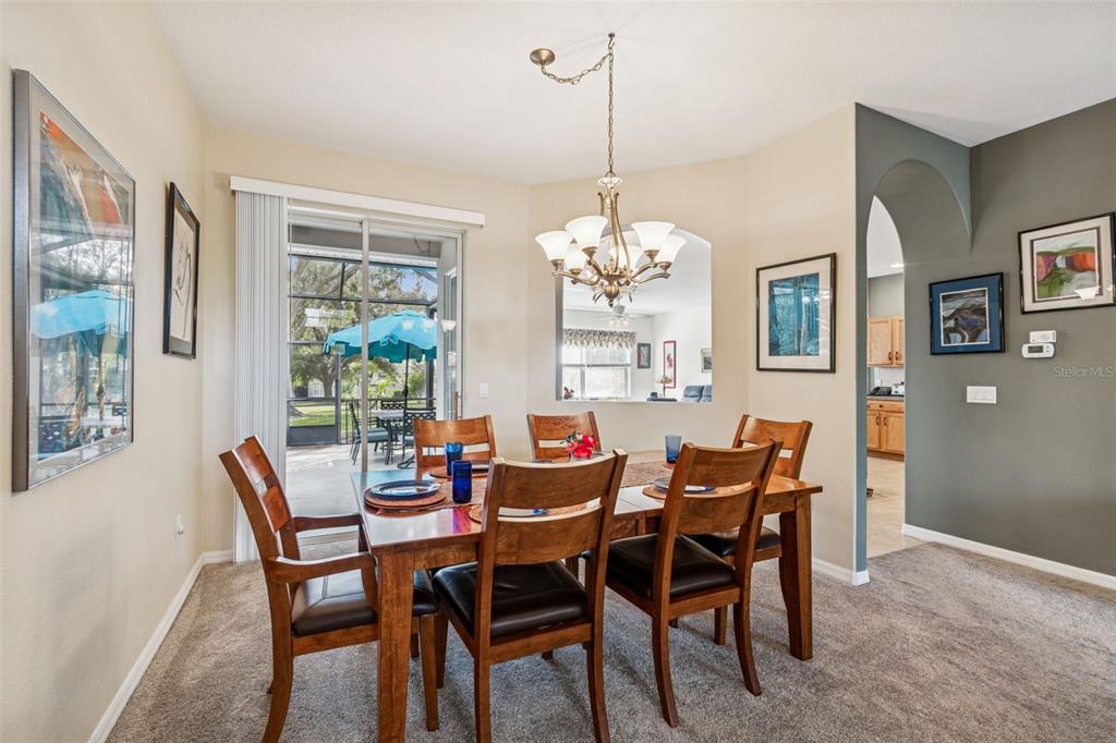 A dining room with a wooden table, six chairs, a chandelier, and a sliding glass door — 18902 GRAND CLUB DRIVE, HUDSON, FL