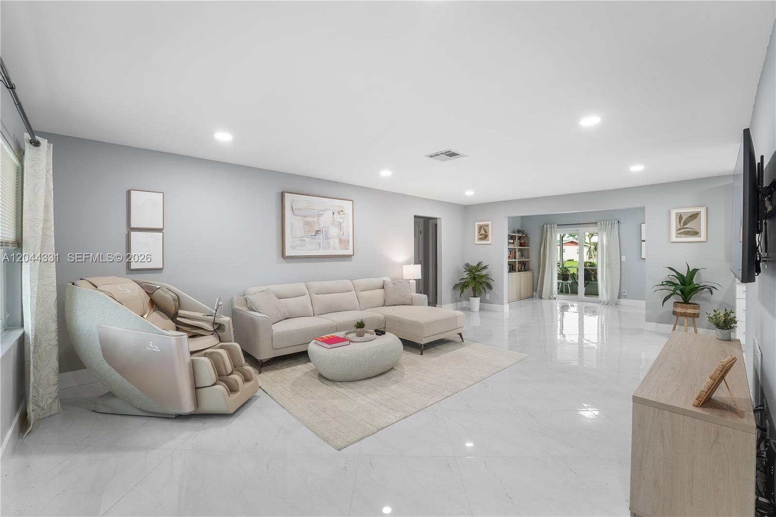 A living room features a sectional sofa, massage chair, light-colored tile floors, and a television — 14307 Amapola Dr, Delray Beach FL 33484, DELRAY BEACH, FL
