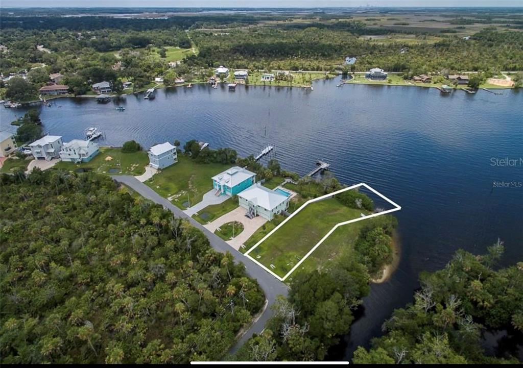 An aerial view shows a vacant waterfront lot outlined in white next to a house — 10863 W XANADU PATH, HOMOSASSA, FL