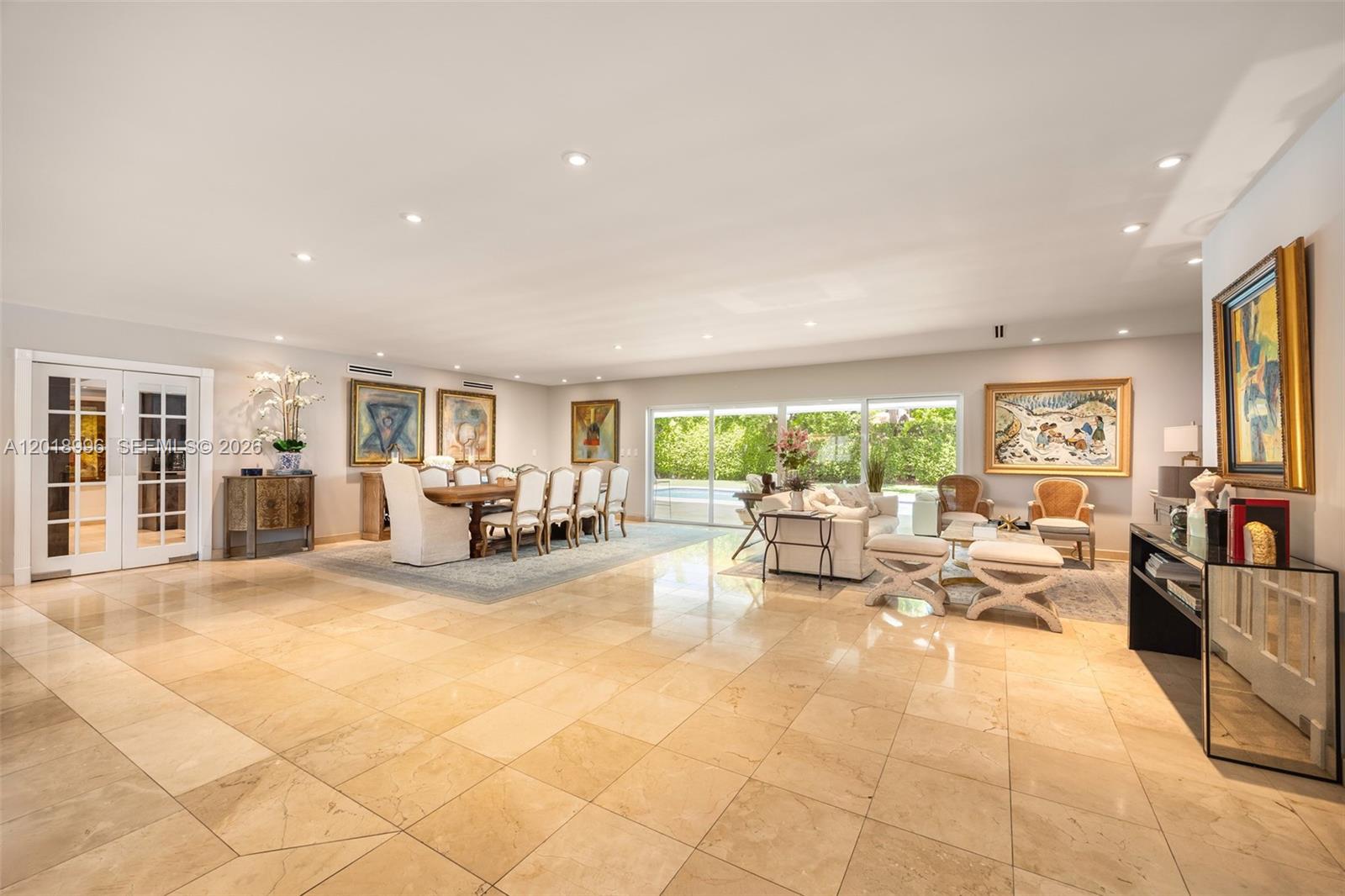 A spacious open-concept living and dining area features large beige floor tiles and glass doors — 7230 Vistalmar St, Coral Gables FL 33143, CORAL GABLES, FL